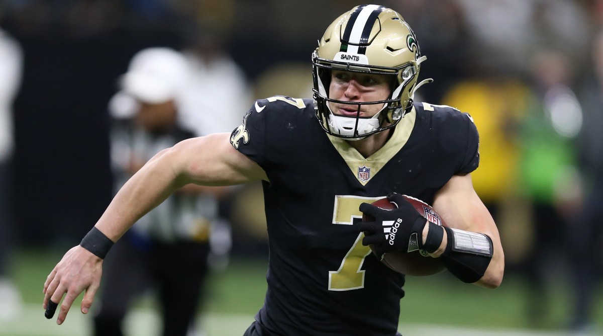 Taysom Hill runs with the football during a game.
